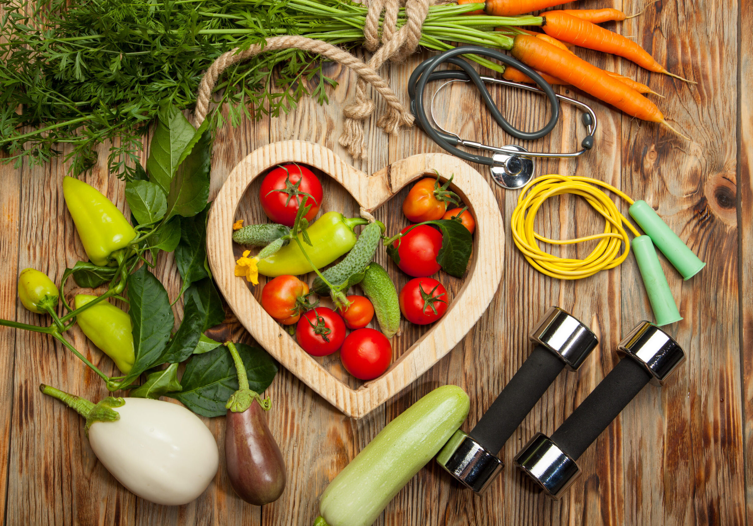 Sport and diet. Healthy lifestyle. Vegetables, dumbbells. Peppers, tomatoes, garlic, onion radish in a heart on white background
